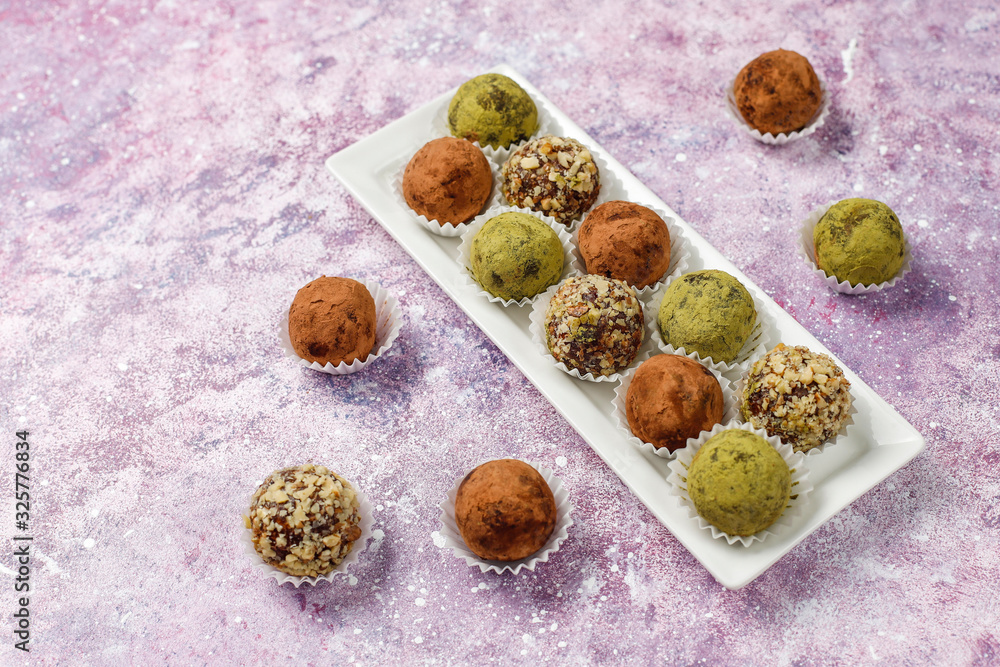 Homemade healthy vegan raw energy truffle balls with dates and walnuts,matcha powder,cocoa powder on light background Homemade healthy vegan raw energy truffle balls with dates and walnuts,matcha powder,cocoa powder on light background