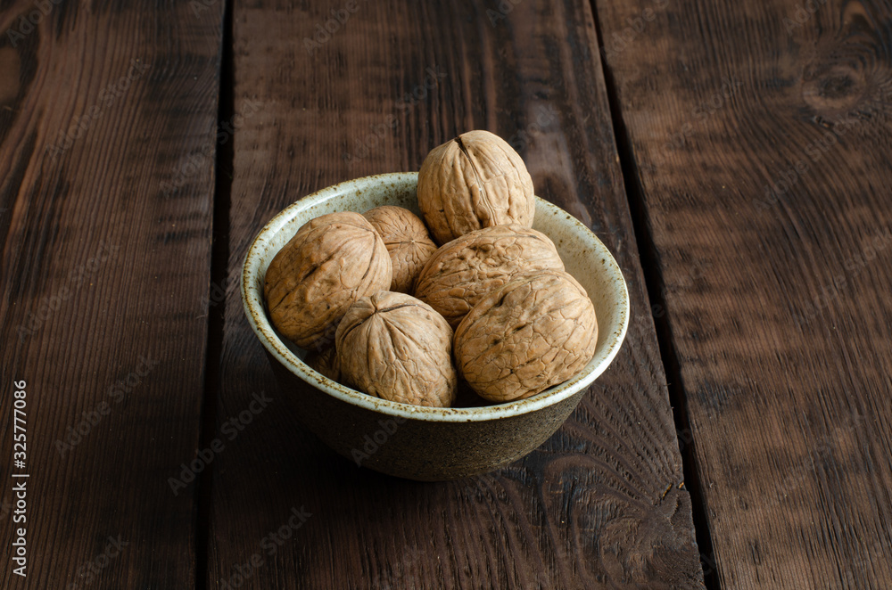 walnut with shell in bowl on wooden background. walnut with shell in bowl on wooden background.