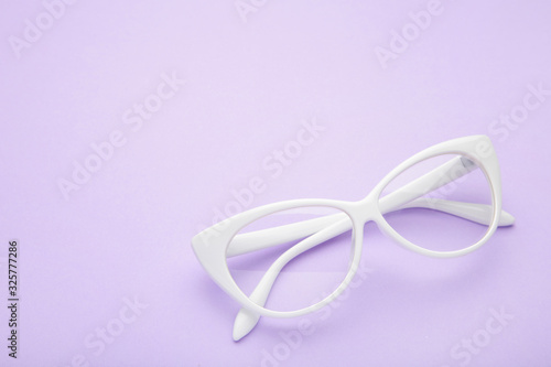 White glasses on lilac background, top view