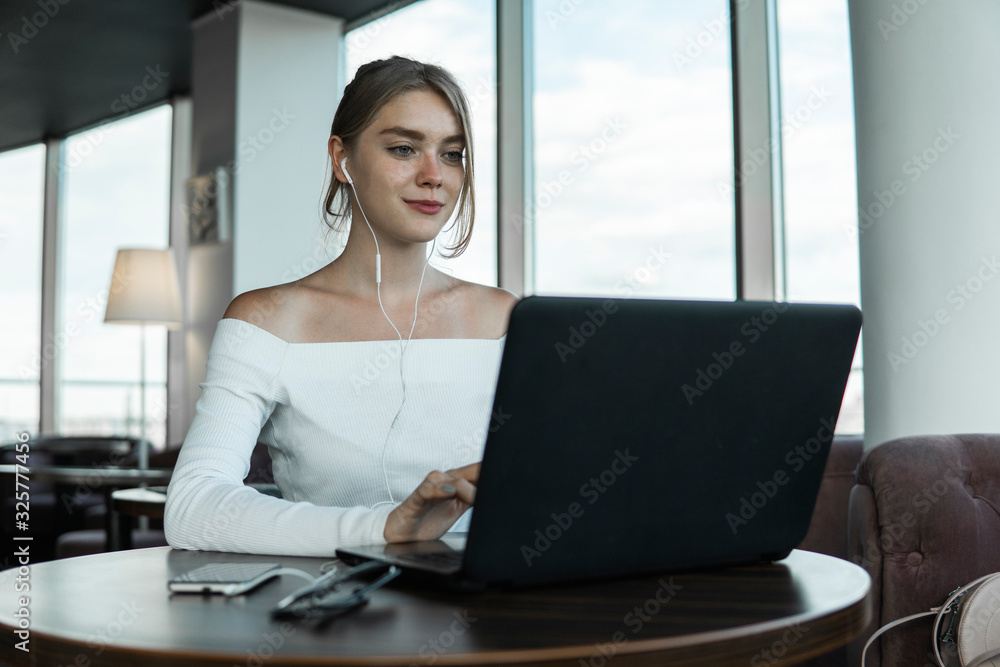 Young business woman using laptop computer in cafe or in coworking. Blond female working on laptop in an outdoor cafe. Young business woman using laptop computer in cafe or in coworking. Blond female working on laptop in an outdoor cafe.
