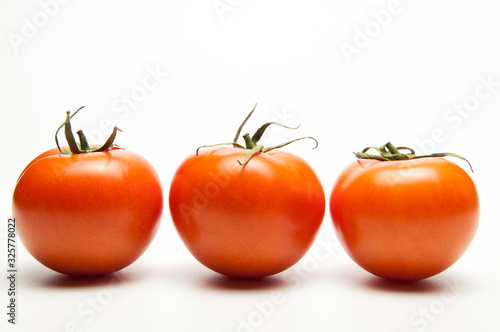 Fresh tomatoes. Red with a green spine. Vegetarian food. On white background