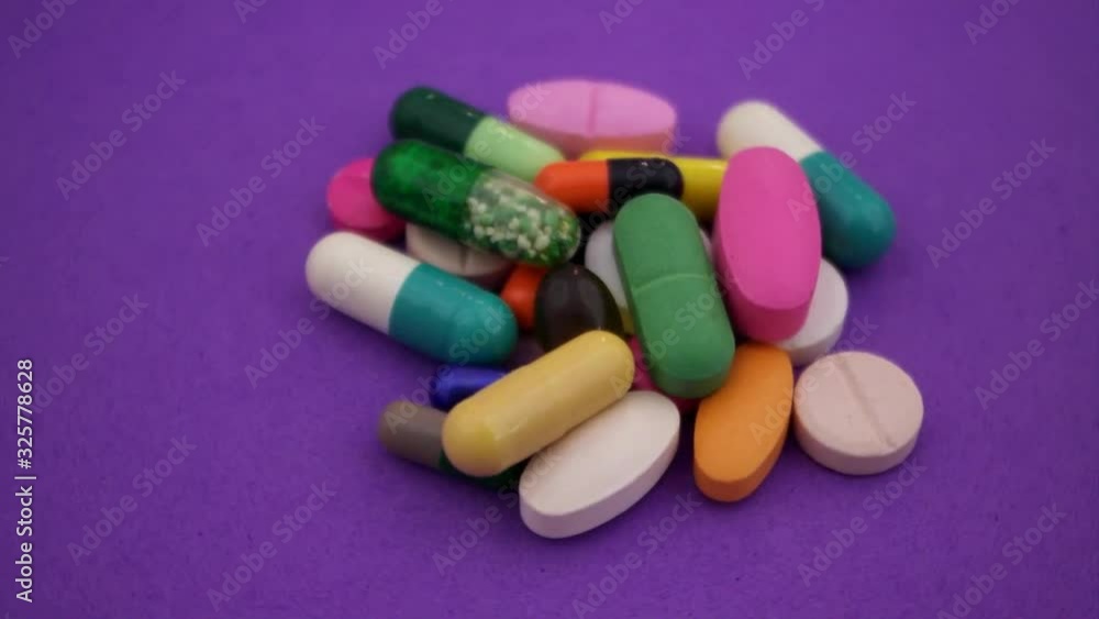 Heap of colorful pills and drugs on purple background Heap of colorful pills and drugs on purple background
