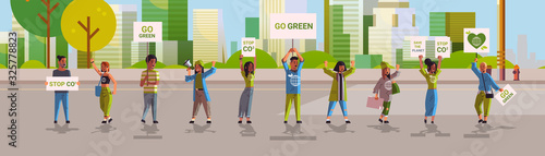 environmental activists holding posters go green save planet strike concept protesters campaigning to protect earth demonstrating against global warming cityscape background horizontal full length