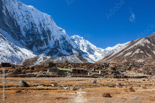 Himalayan lodges on the way to Tashi Lapcha pass. Village and pasture in Khumbu area in Nepal. Beautiful snowy mountains landscape. photo