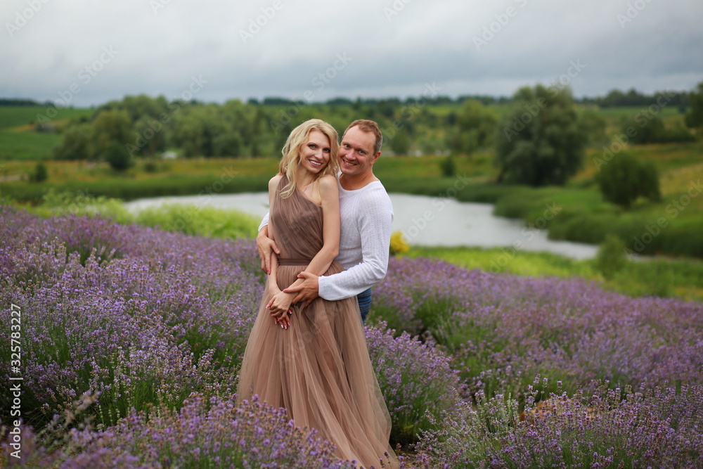  happy couple cuddling, having fun and relaxing in a lavender field in summer