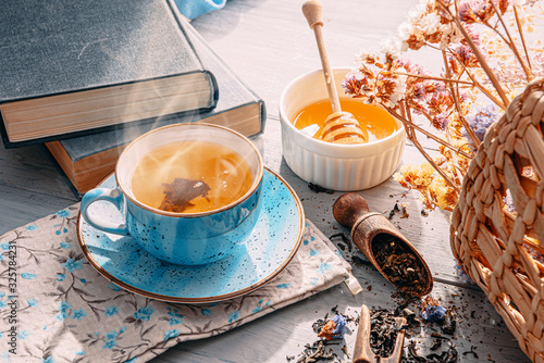 Fotografija tea and a book in the spring sunshine. near honey and flowers