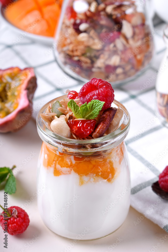 Natural yogurt, granola and mashed passion fruit and mango layered in a glass jar. Breakfast idea Natural yogurt, granola and mashed passion fruit and mango layered in a glass jar. Breakfast idea