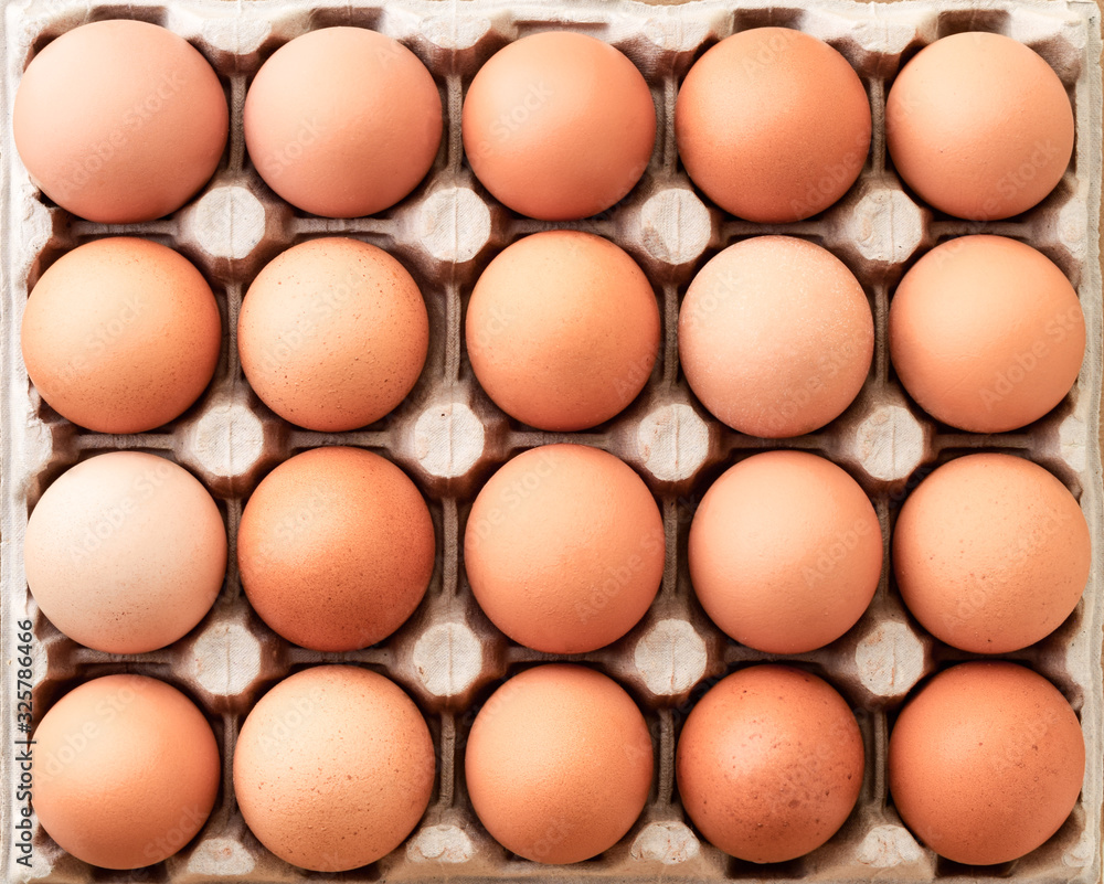 Closeup of many fresh brown eggs in tray. Background
