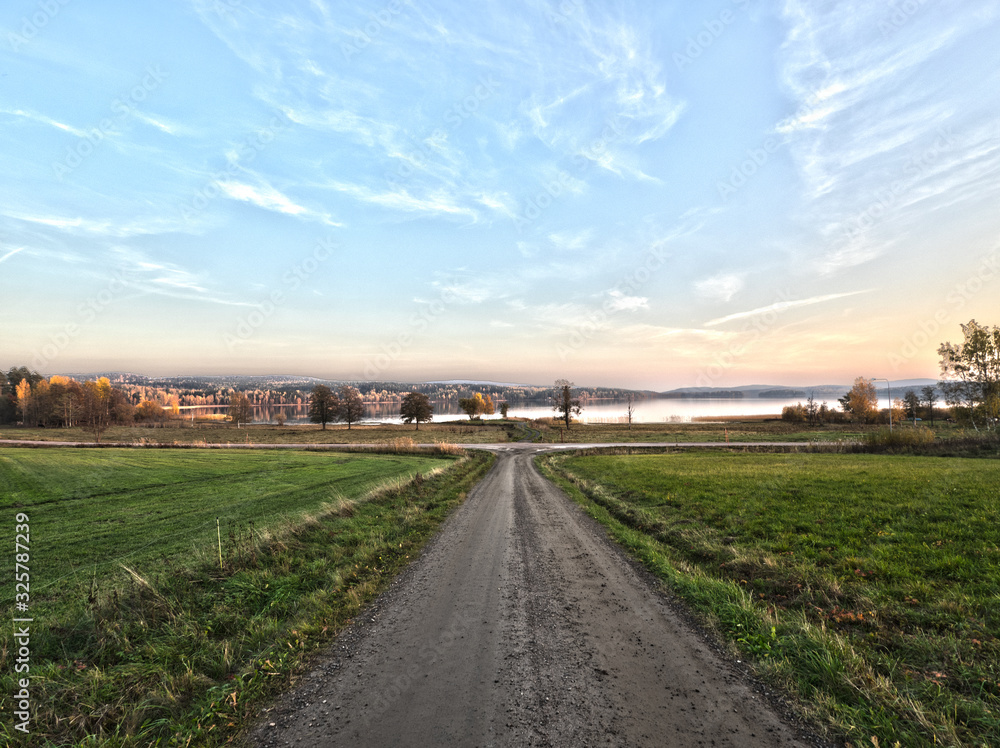 Obraz premium long straight country road leading to lake