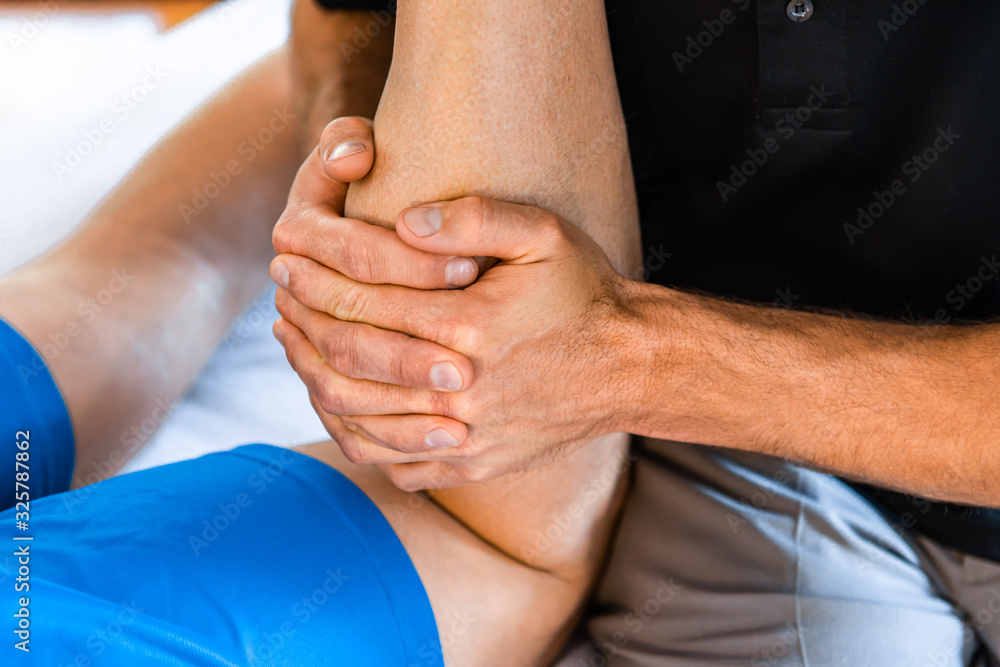 Φωτογραφία An unrecognizable professional sports masseur working on legs of sportsman after injury