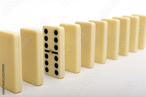 One domino standing out from the row. Domino stones on white backround.