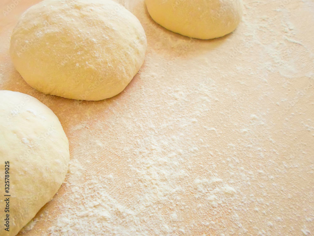three balls of pizza dough on a rustic wooden background with flour dust three balls of pizza dough on a rustic wooden background with flour dust
