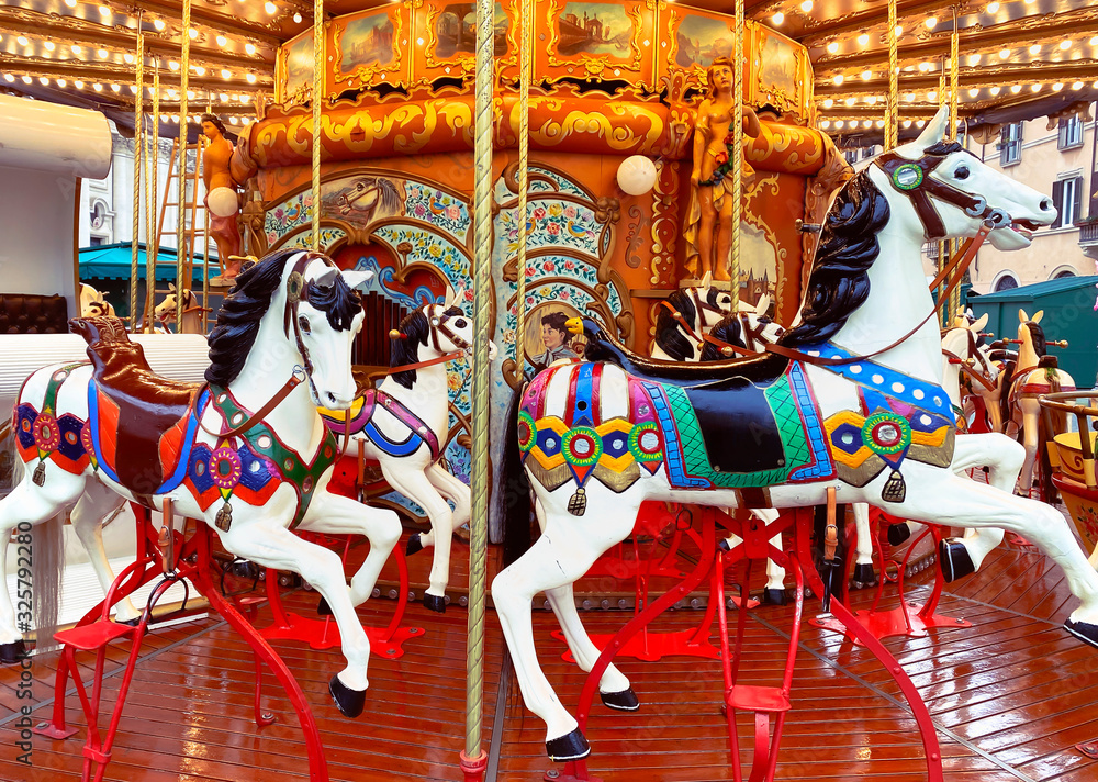 white painted horses in a carousel decorated with lights and gold