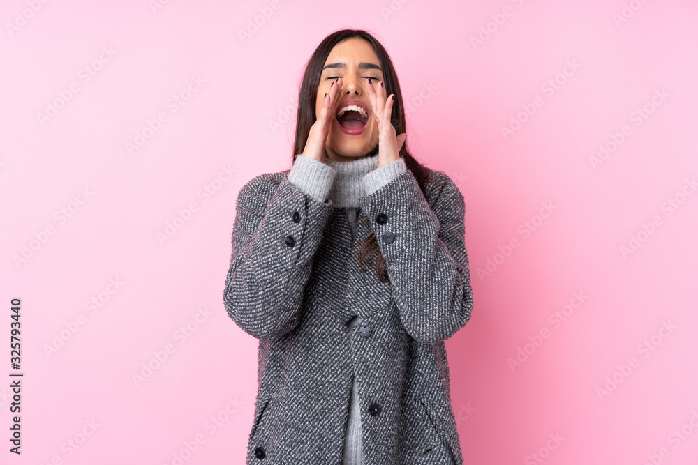 Young brunette woman over isolated pink background shouting and announcing something