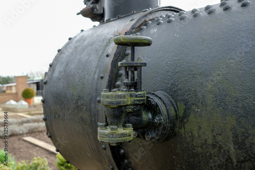 Close-up view of steam pressure control valves seen on the side of an antique stream traction engine dating from early last century.