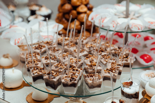 Wedding candy bar table. Cakes and other sweet festive desserts. Different delicious desserts and cakes on the buffet table. Delicious and tasty dessert table with cupcakes shots at reception closeup.