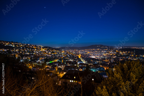 Germany, Stuttgart, View above skyline houses, roofs and streets iluminated by night in full moon moonlight magical atmosphere