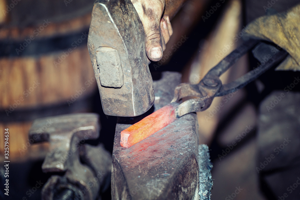 Blacksmith working metal with hammer on the anvil Blacksmith working metal with hammer on the anvil