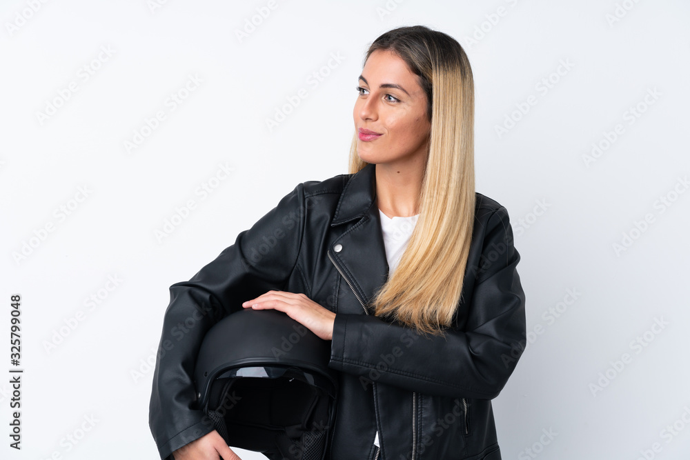 Young Uruguayan woman with a motorcycle helmet over isolated white background looking to the side Young Uruguayan woman with a motorcycle helmet over isolated white background looking to the side