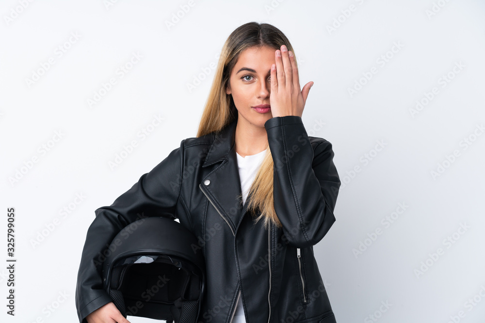 Young Uruguayan woman with a motorcycle helmet over isolated white background covering a eye by hand Young Uruguayan woman with a motorcycle helmet over isolated white background covering a eye by hand
