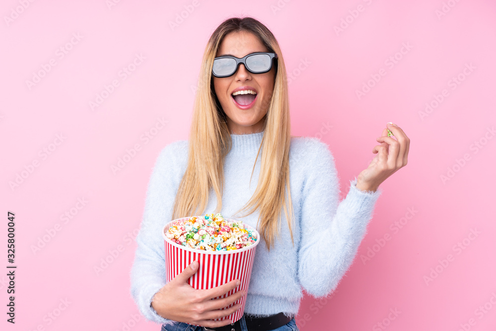 Young Uruguayan woman over isolated pink background with 3d glasses and holding a big bucket of popcorns Young Uruguayan woman over isolated pink background with 3d glasses and holding a big bucket of popcorns
