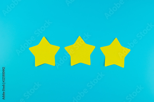 three star yellow paper note on blue background with copy space for text. Customer reviews, feedback, rating, ranking and service concept.