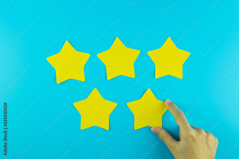 customer holding five star yellow paper note on blue background. Customer reviews, feedback, rating, ranking and service concept. customer holding five star yellow paper note on blue background. Customer reviews, feedback, rating, ranking and service concept.