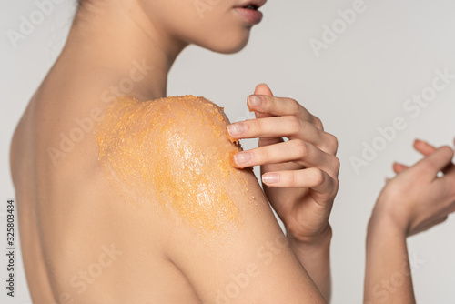 Fototapeta cropped view of girl applying sugar scrub on shoulder, isolated on grey