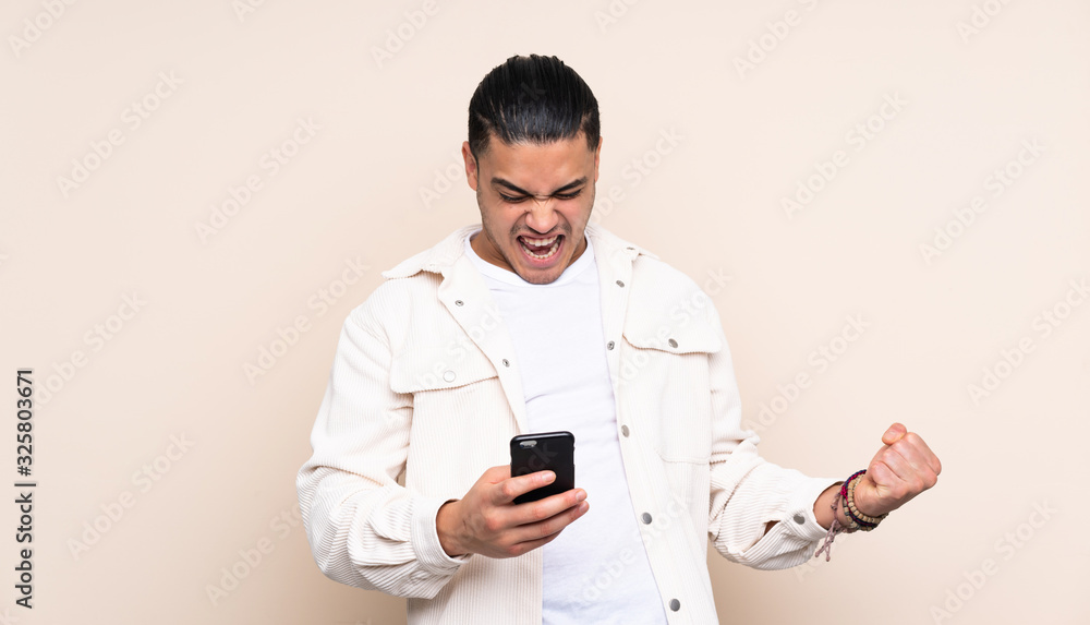 Asian handsome man over isolated background with phone in victory position Asian handsome man over isolated background with phone in victory position