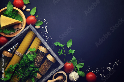 Spaghetti and spices in a wooden box. italian spaghetti pasta with tomato, cheese and basil on table. Flat-lay