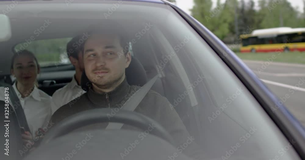 Man drives a car with a female and male passengers and picking them to work view through front window. Man drives a car with a female and male passengers and picking them to work view through front window.