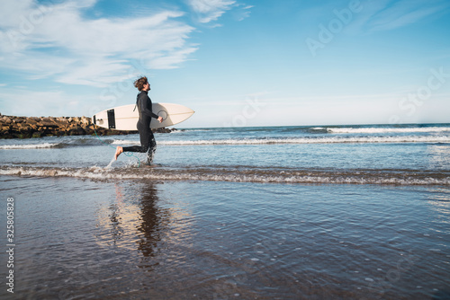 Surfer entering into the water with his surfboard.