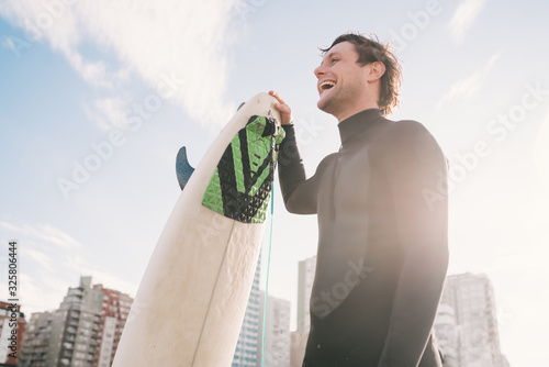 Surfer standing at the beach with surfboard.