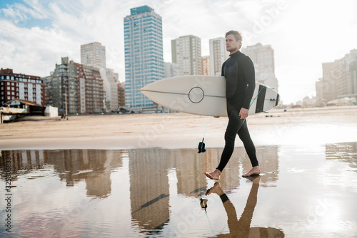 Surfer standing in the ocean with his surfboard.