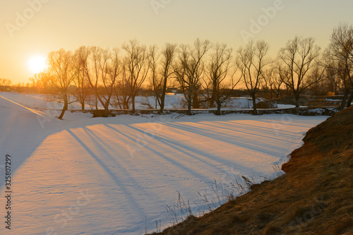 Evening spring landscape with melting snow and long shadows
