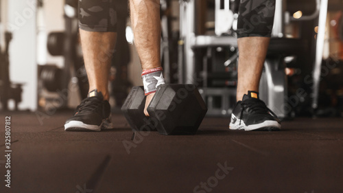 Cropped photo of athlete man while getting ready for fit training with dumbbells at the gym