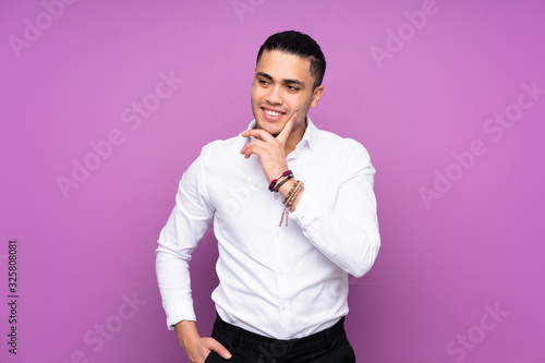 Asian handsome man isolated on blue background thinking an idea while looking up