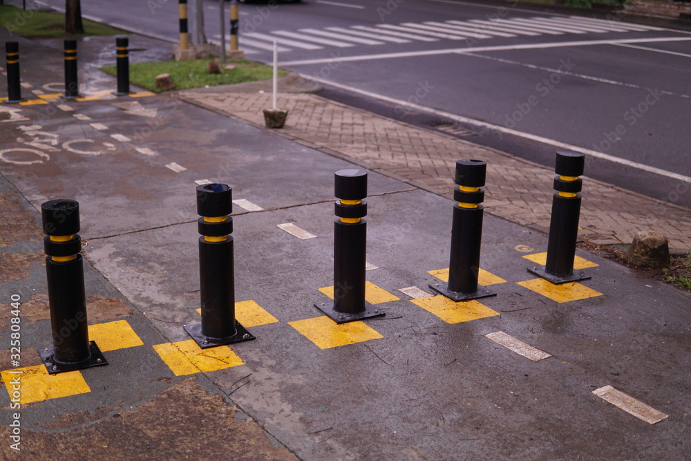 Restrictive posts between the pedestrian sidewalk and the road. poles of  yellow-black color, striped Stock Photo | Adobe Stock