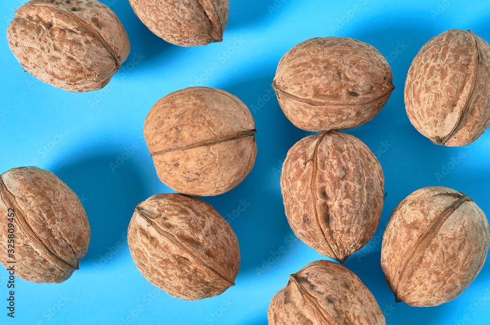 Scattered whole ripe walnuts on blue background. Top view Scattered whole ripe walnuts on blue background. Top view