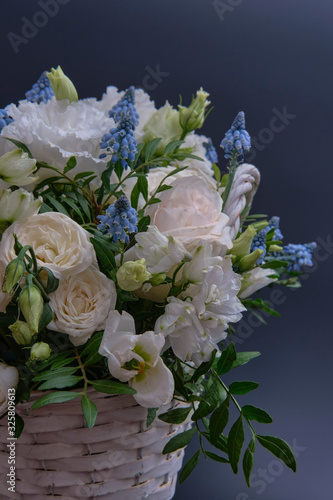 Bouquet. Composition of fresh, delicate flowers in a white basket against a dark background.