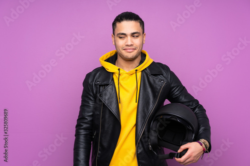 Man with a motorcycle helmet isolated on purple background standing and looking to the side
