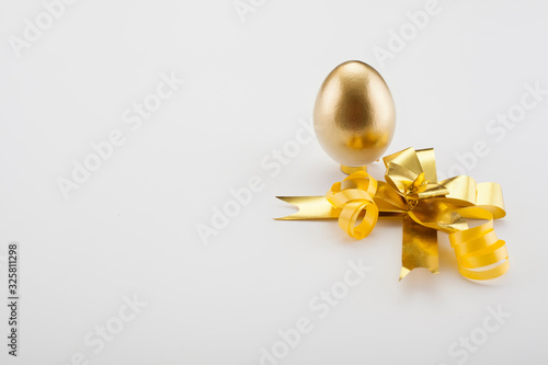 Golden eggs are decorated with a gold bow, located on the edge of the background with a place for text, with copy space. Concept backgrounds for Easter.