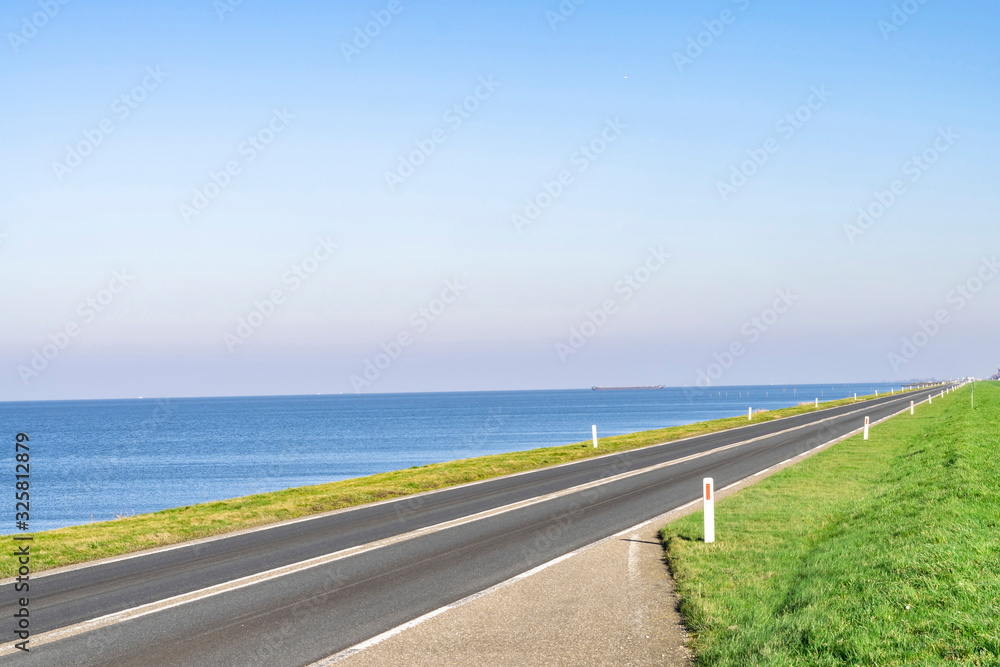 Perspective in a landscape with horizon, road, sky and water. Seascape with blue sea and highway on the coast. Traveling by car during the summer holidays. Perspective in a landscape with horizon, road, sky and water. Seascape with blue sea and highway on the coast. Traveling by car during the summer holidays.