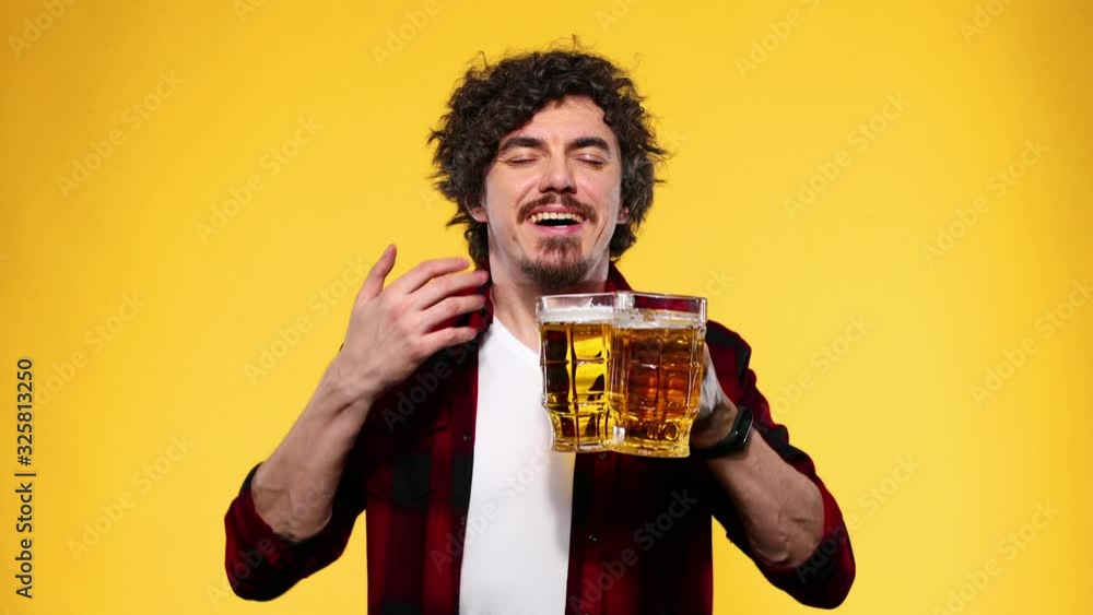 Saint Patrick Day. Young Oktoberfest man serving big beer mug with drink isolated on yellow background. Guy showing thumbs up sign with fingers. Saint Patrick Day. Young Oktoberfest man serving big beer mug with drink isolated on yellow background. Guy showing thumbs up sign with fingers.