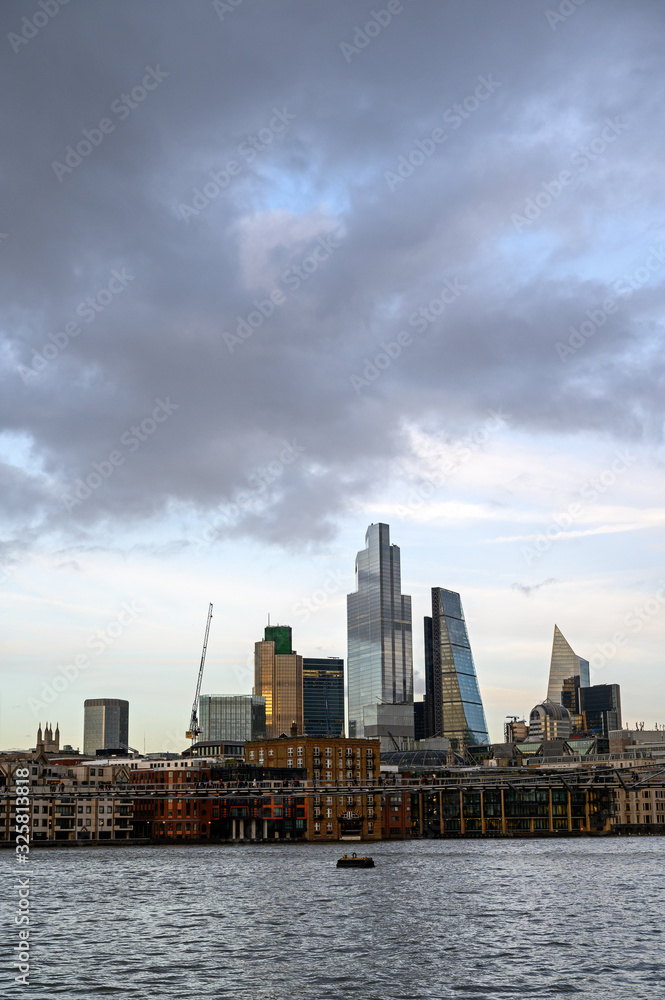 City of London in the UK. Landscape view over the River Thames to the city of London. Cityscape of the business district with skyscrapers, dramatic clouds and river in London, England 2020.