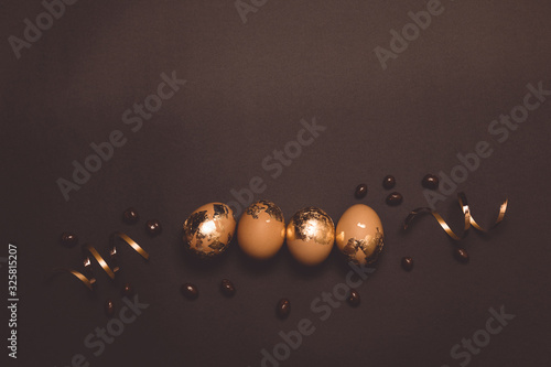 Photography Beautiful brown and golden easter eggs on dark background , flat lay