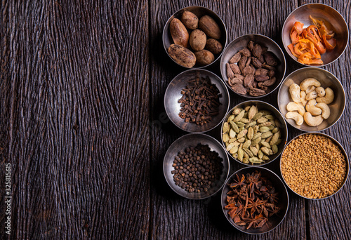 Set of various spices on rustic wood background. Pepper, turmelic, paprika, basil, rosemary, chilly, cardamom, cinnamon, anise. Top view with copy space.