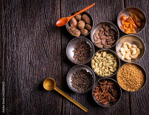 Set of various spices on rustic wood background. Pepper, turmelic, paprika, basil, rosemary, chilly, cardamom, cinnamon, anise. Top view with copy space. photo