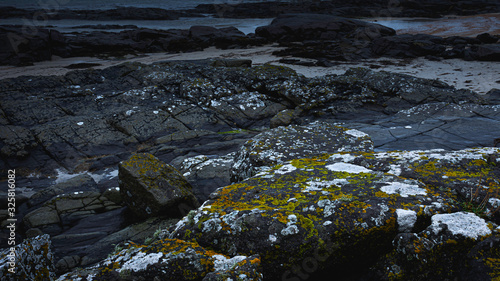 Sanna beach on west coast of Scotland on gloomy day.Black, volcanic mossy basalt rocks on diverse Scottish coastline.Dark seascape scene with atmospheric mood and blue tones.Dramatic coastal landscape © Jazzlove