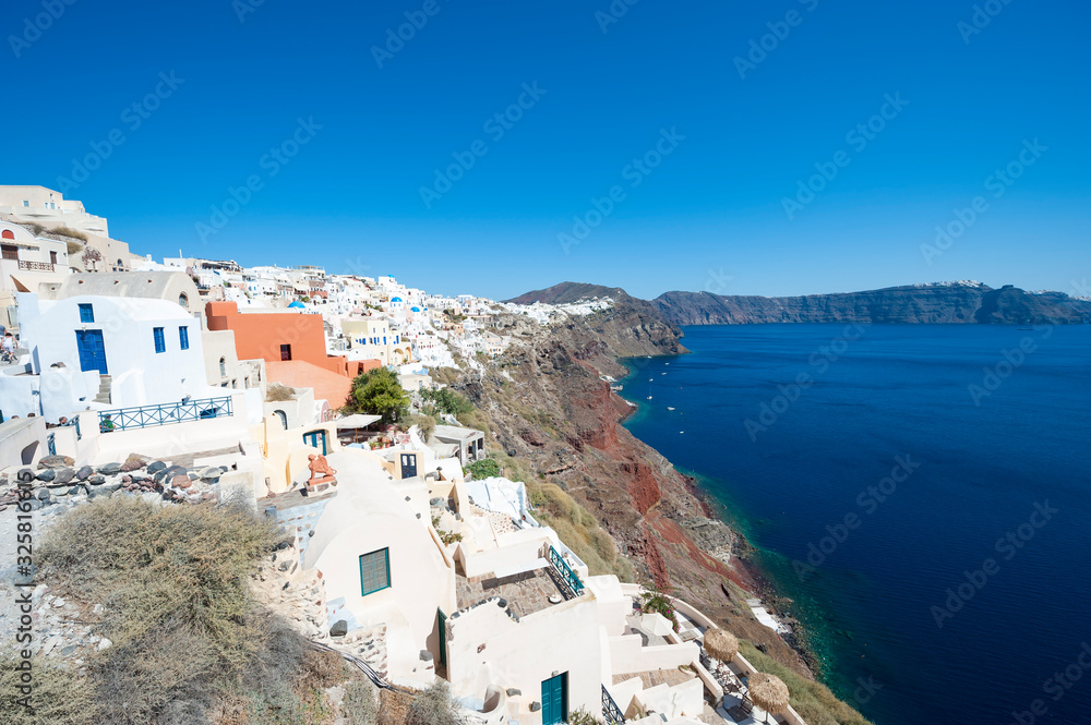 Sunny hillside view of Oia village under Mediterranean blue sky in Santorini, Greece